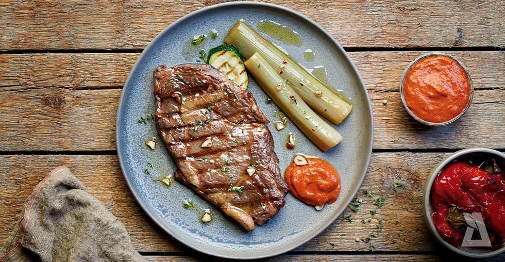 Entrecot a la brasa amb calçots confitats, salsa romesco i picada d'avellanes